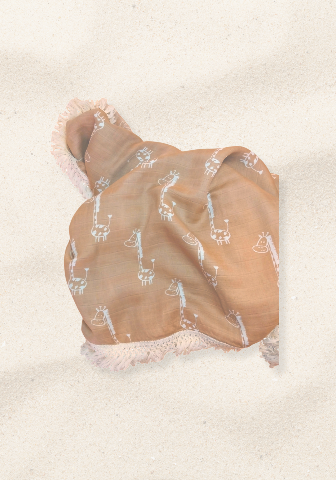 Rolled mocha-colored organic cotton baby blanket featuring white giraffe illustrations and white fringed edges, displayed on a sand background.
