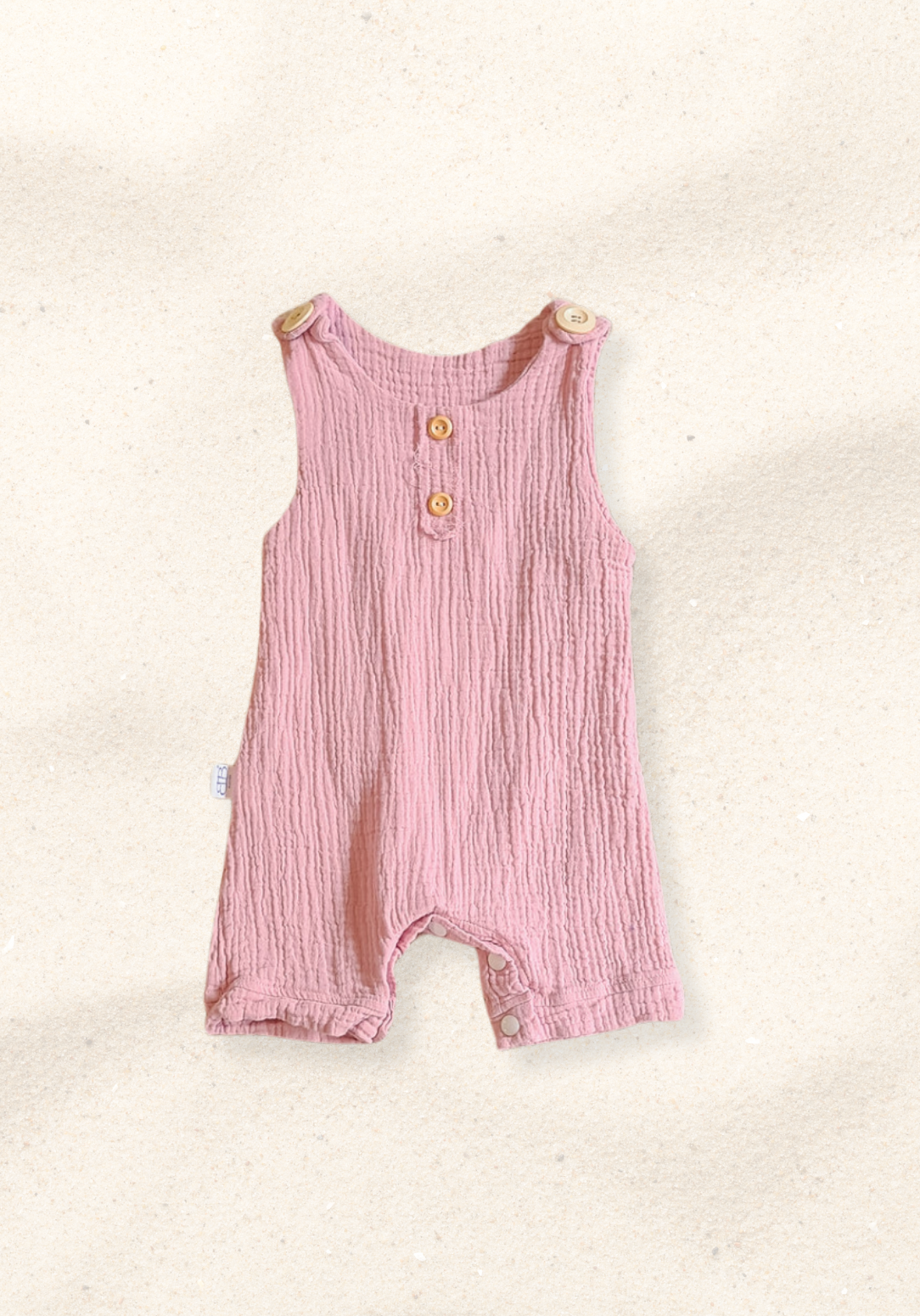 Dusty pink organic cotton baby overall onesie with wooden button shoulder straps and soft elastic leg openings