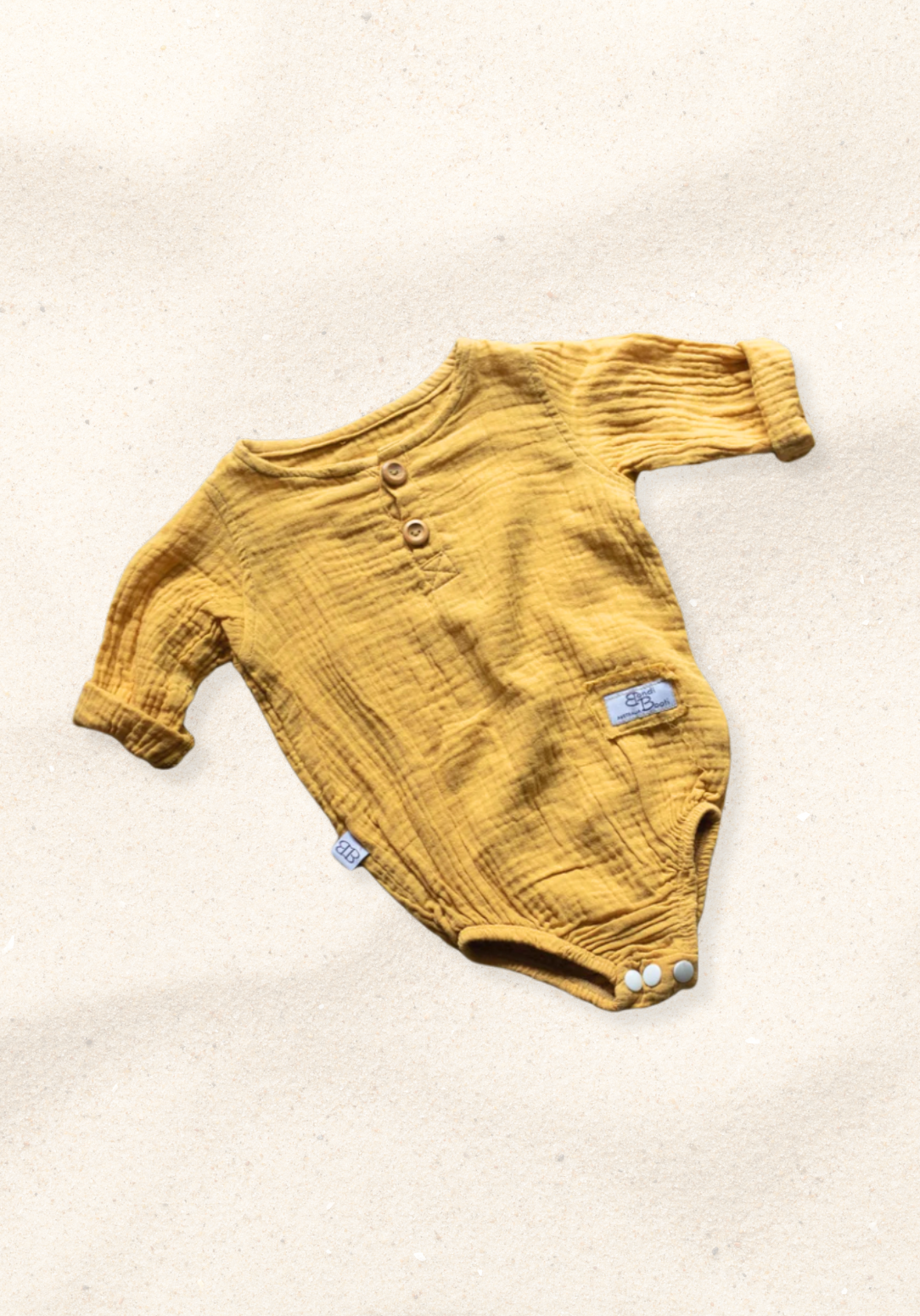 Mustard yellow long sleeve baby romper made from organic cotton with wooden buttons and snap closure.