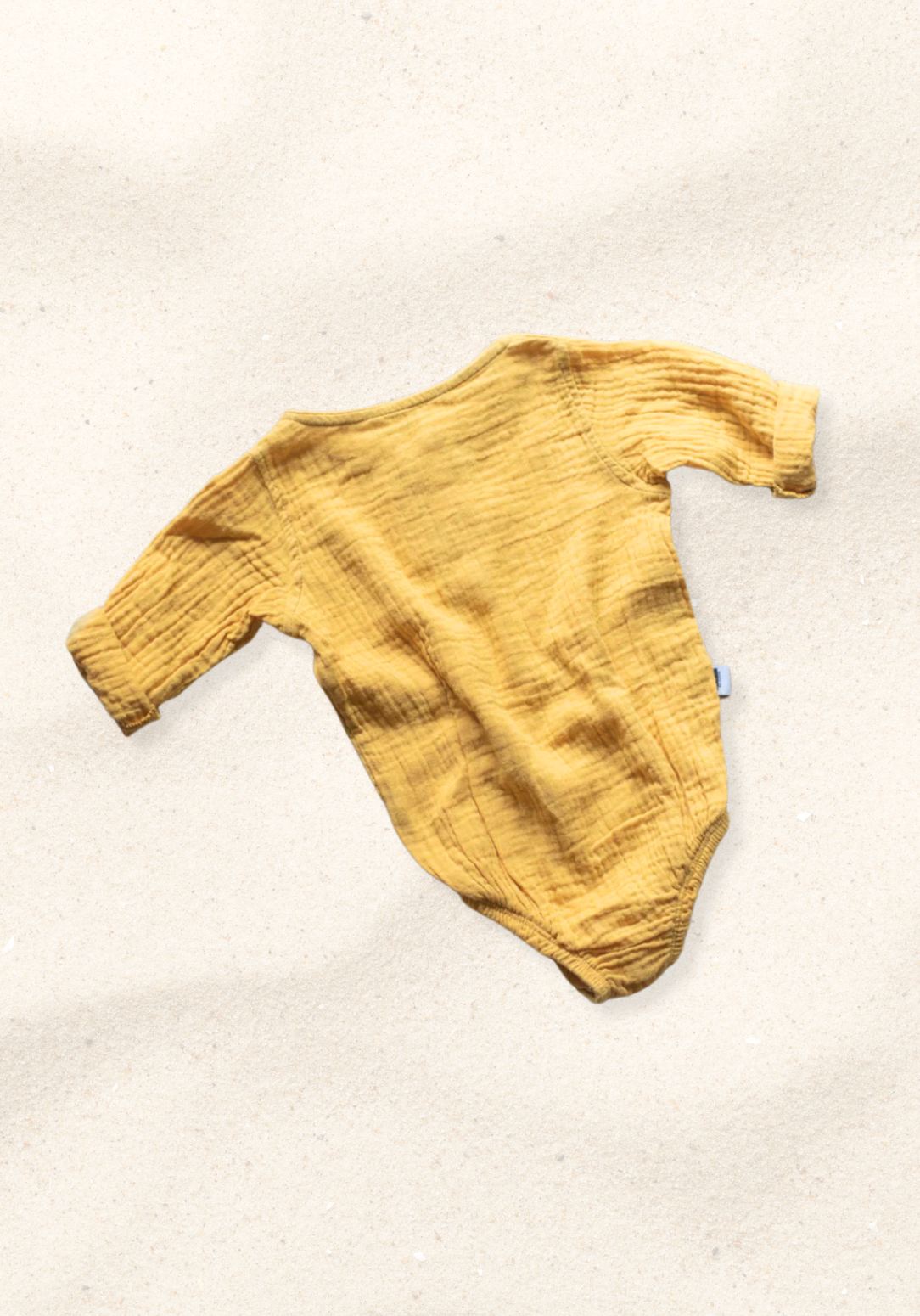 Mustard yellow long sleeve baby romper made from organic cotton with wooden buttons and snap closure.
