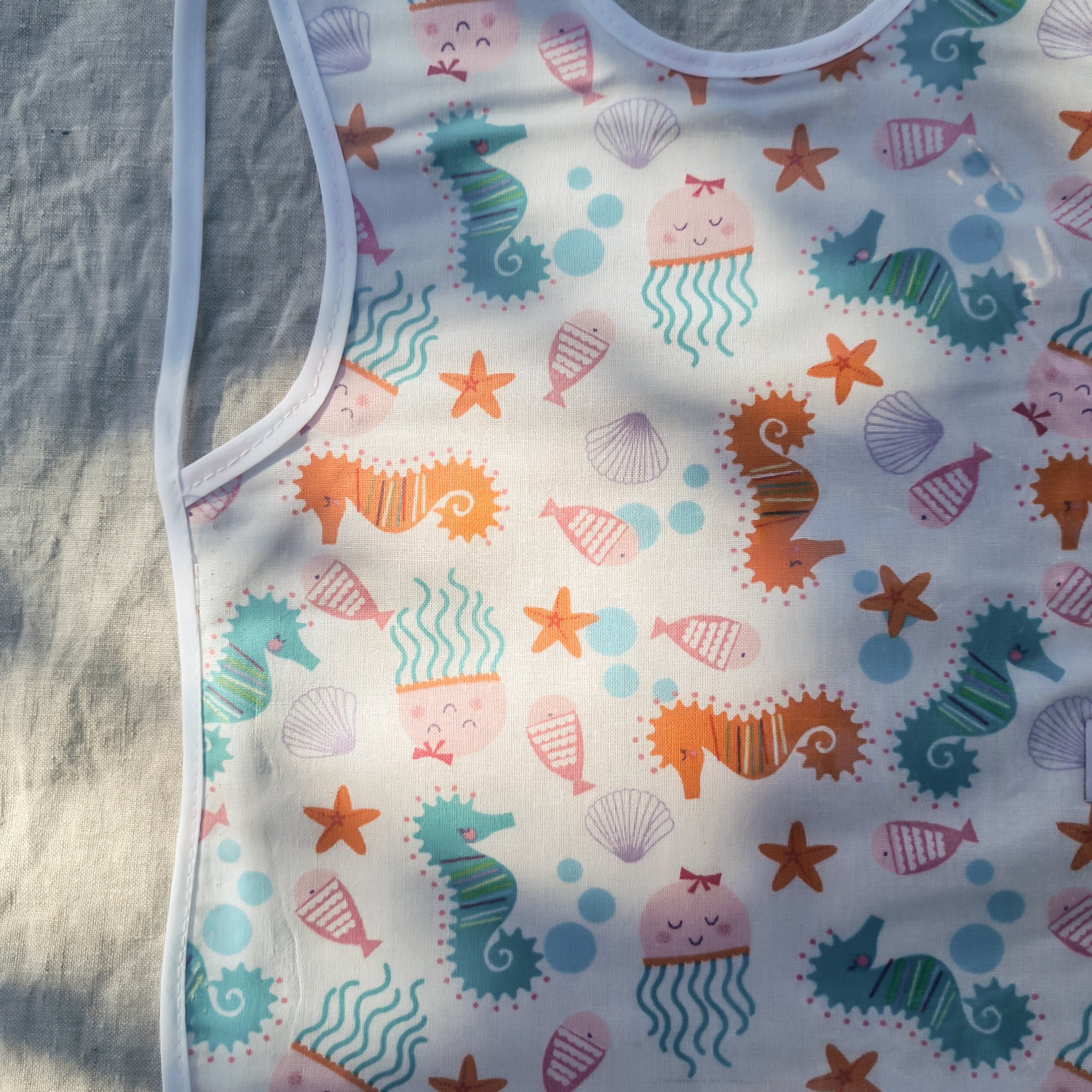 Laminated baby bib with seahorse and seashells design