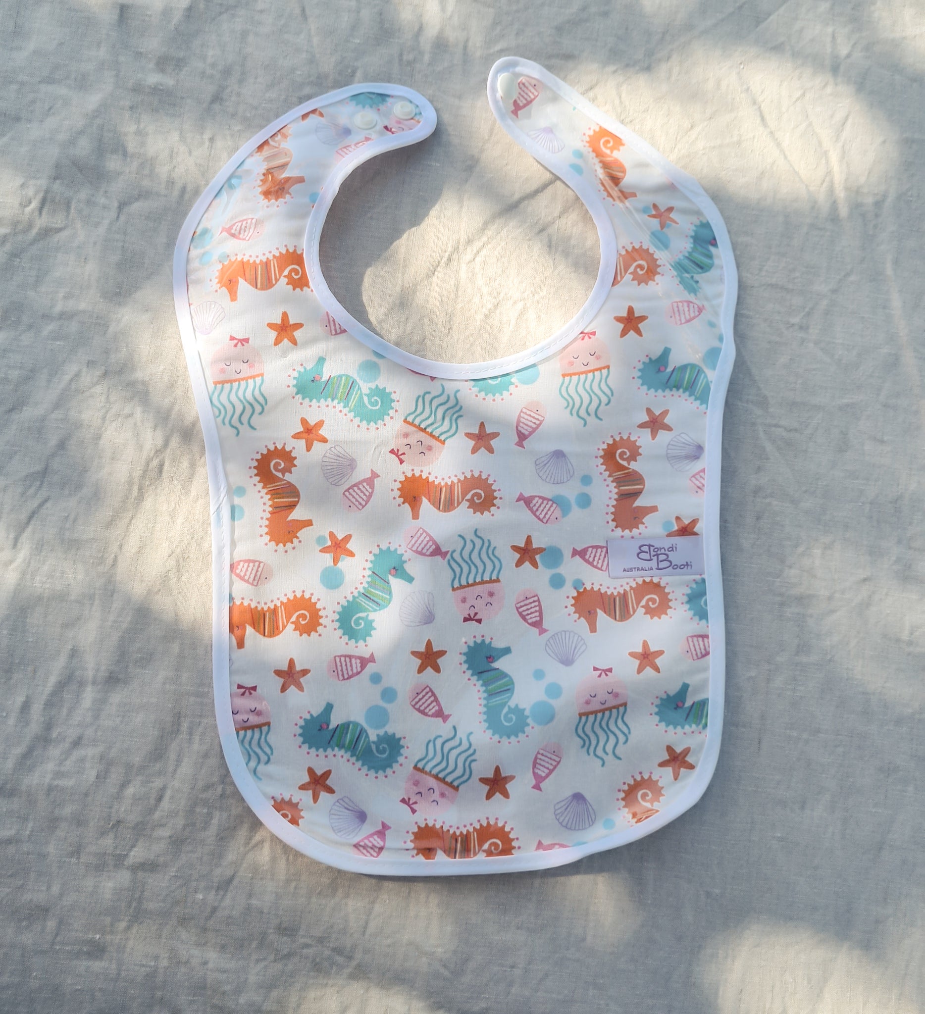 Laminated baby bib with seahorse and seashells design