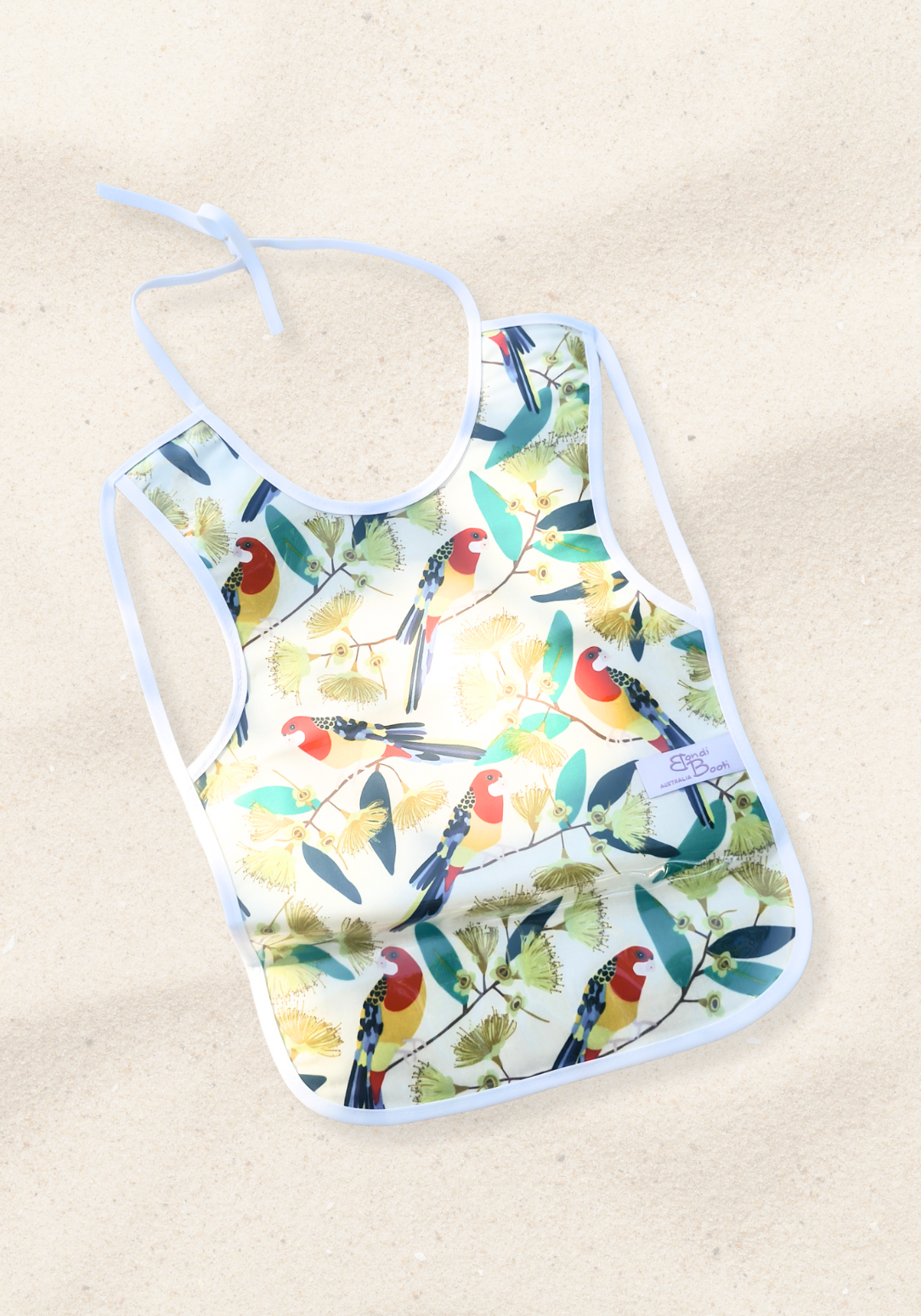 Laminated toddler feeding bib with a vibrant print of red and yellow native Australian birds perched on eucalyptus branches, white trim edges, and tie closure, displayed flat on a sand background.