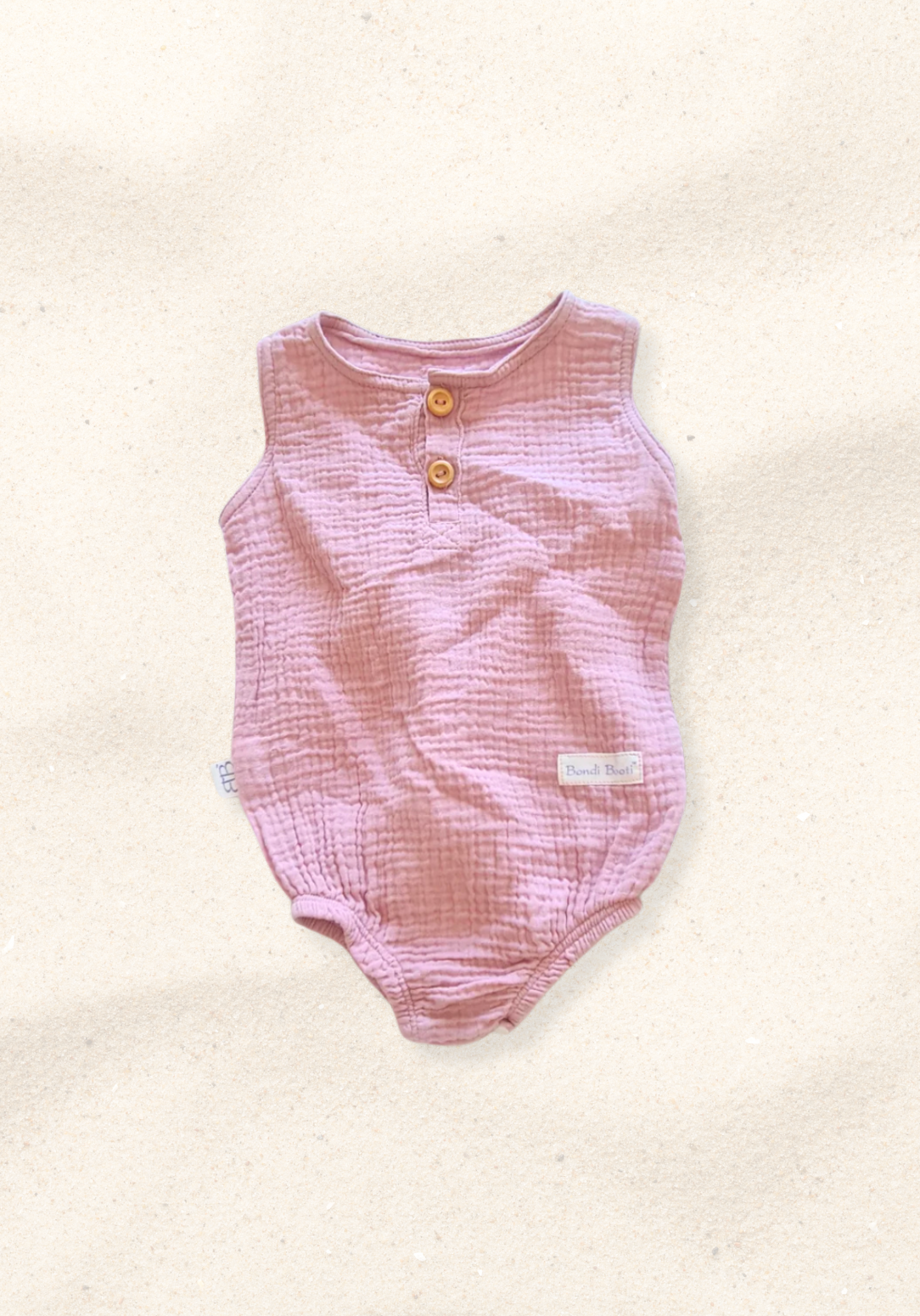 Organic cotton baby romper in dusty pink with snap buttons at the bottom and elasticised leg bands.