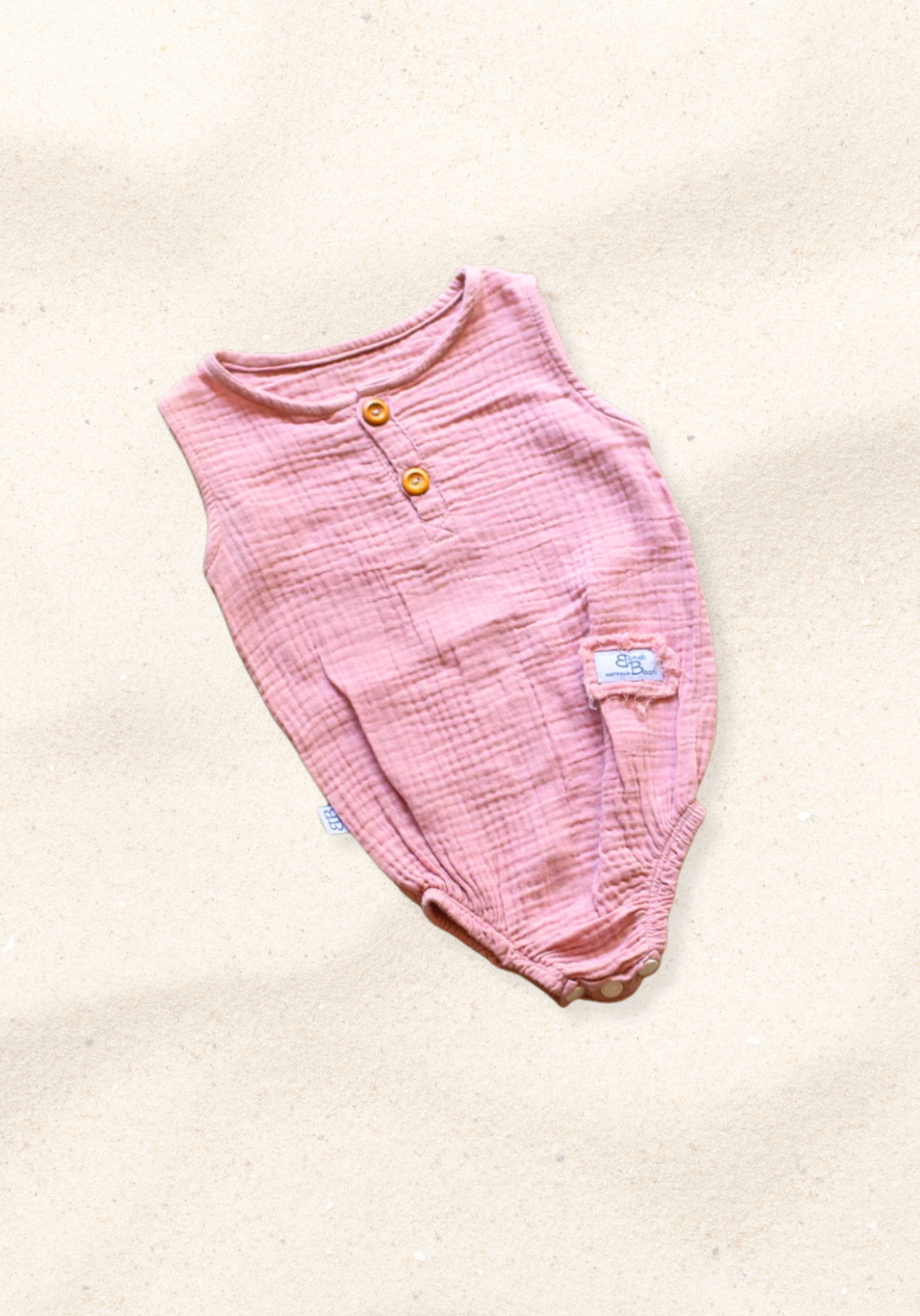 Organic cotton baby romper in dusty pink with snap buttons at the bottom and elasticised leg bands.