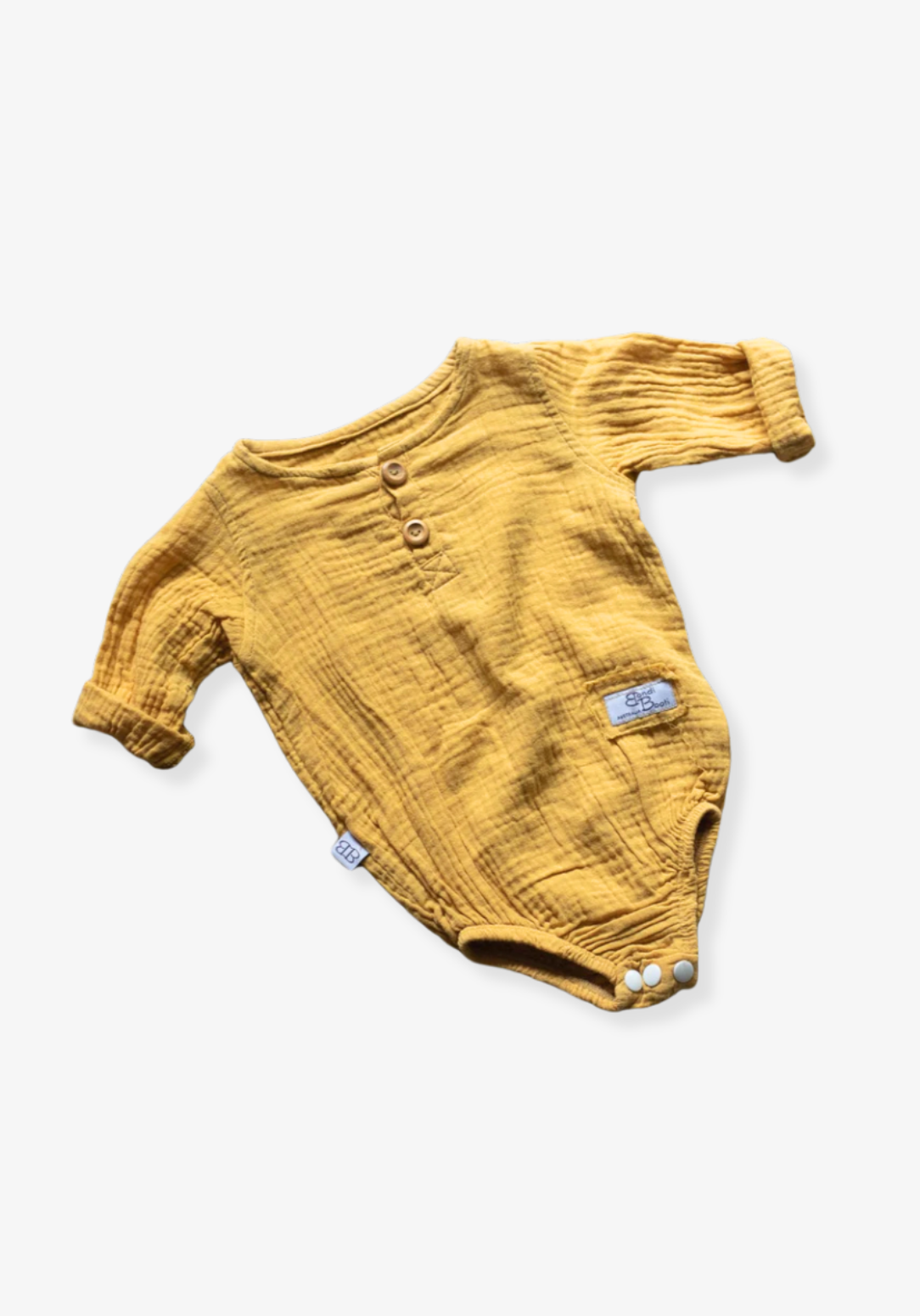 Mustard yellow long sleeve baby romper made from organic cotton with wooden buttons and snap closure.