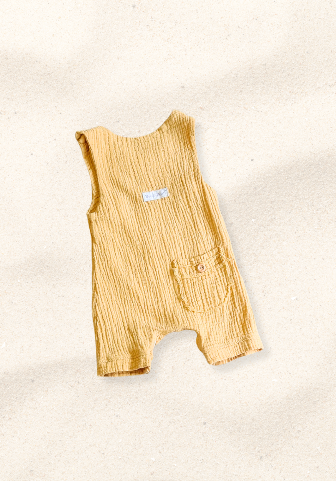Mustard-colored organic cotton baby overall onesie with easy-change snaps on the bottom and wooden buttons on the shoulders.